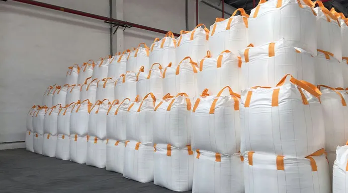 Rows of white anti-static FIBC bags with orange loops in a clean warehouse.